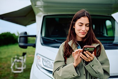 A user interacting with a mobile application on her smartphone outside a specialty vehicle, illustrating sustaining IoT product engineering services.