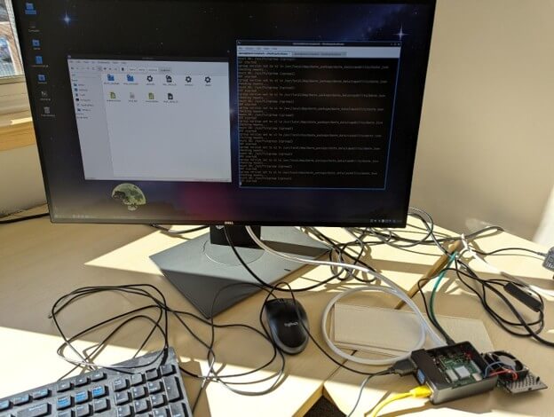 A Raspberry Pi 4 connected to a Dell monitor, keyboard, and mouse, running a Dante Embedded Platform loopback test via Ethernet and USB.